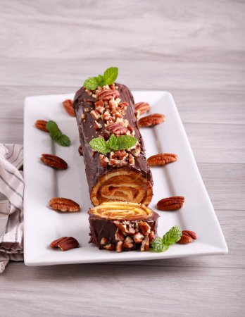 Photo for Sweet roll with caramel filling with chocolate coating and pecan nuts - Royalty Free Image