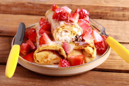 Photo for Crepe rolls with cottage cheese and raisin filling with condensed milk and strawberry topping - Royalty Free Image