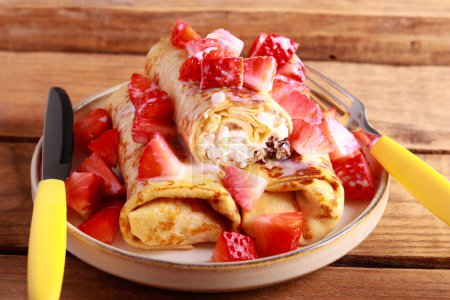 Photo for Crepe rolls with cottage cheese and raisin filling with condensed milk and strawberry topping - Royalty Free Image