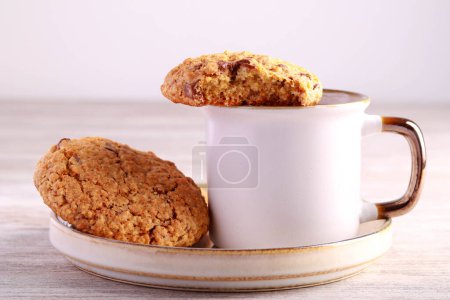 Téléchargez les photos : Biscuits à l'avoine avec morceaux de chocolat et noix, servis avec du café noir - en image libre de droit