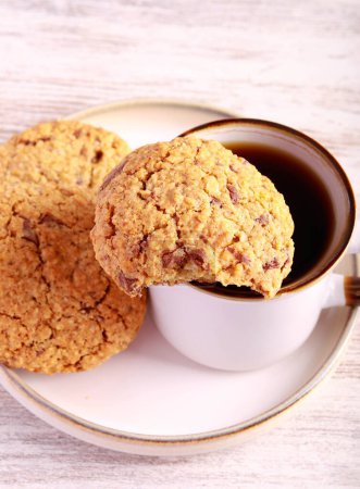 Foto de Galletas de avena con trozos de chocolate y nueces, servidas con café negro - Imagen libre de derechos