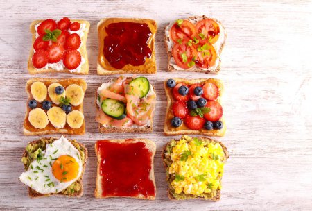 Téléchargez les photos : Sélection de toasts au petit déjeuner avec différentes garnitures salées et sucrées. Sandwich, toasts mix, petit déjeuner ou brunch, concept - en image libre de droit