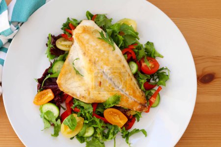 Photo for Fried dorada fish or gilt head breamfish fillet over salad - Royalty Free Image