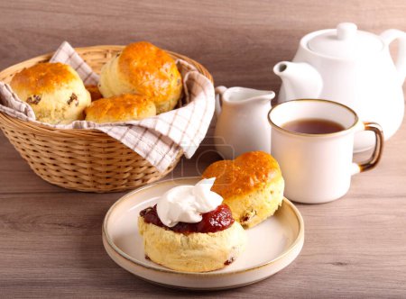 Photo for Classical scones with jam and whipped cream, served with tea - Royalty Free Image