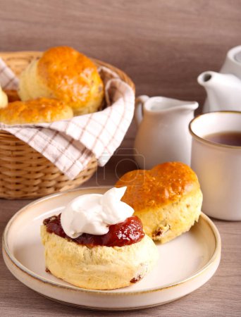 Photo for Classical scones with jam and whipped cream, served with tea - Royalty Free Image
