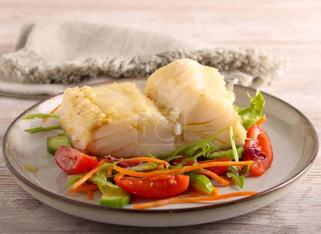 Foto de Filete de bacalao con ensalada en plato - Imagen libre de derechos