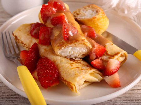 Photo for Crepes rolls with cottage cheese protein filling, with caramel sauce and strawberry topping - Royalty Free Image