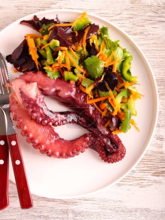 Foto de Tentáculos de pulpo cocidos con ensalada en plato - Imagen libre de derechos