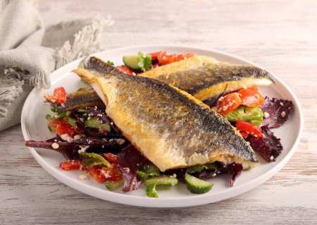 Photo for Fried seabass fillet over salad, on plate - Royalty Free Image