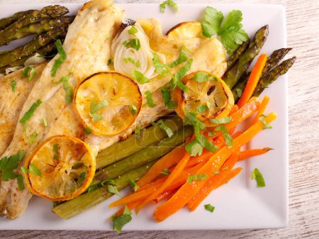 Photo for Lemon fish with asparagus and carrot on plate - Royalty Free Image