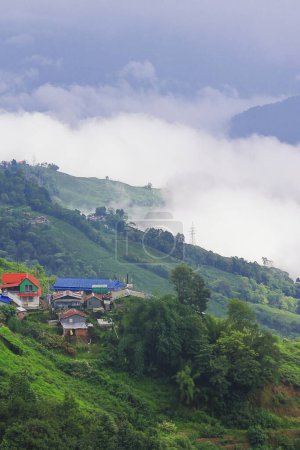 panorama of foggy and cloudy mountain village, on the slopes of himalaya mountains near darjeeling hill station in monsoon season, west bengal, india