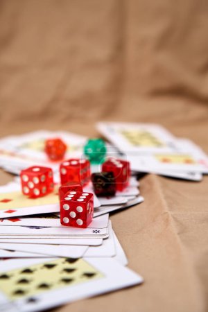 Extended poker cards, several dice of different colors and sizes on a cardboard-like surface.