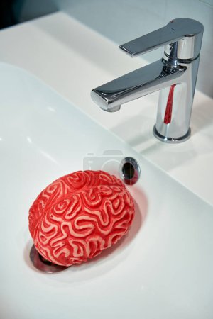 Photo for Depiction of the Brainwashing Concept with a Red Rubber Brain under a Sink Faucet. - Royalty Free Image