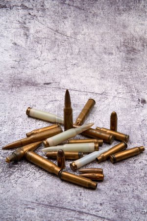 From above of collection of fired golden bullets and unfired cartridges with white plastic case arranged on rough floor at daytime