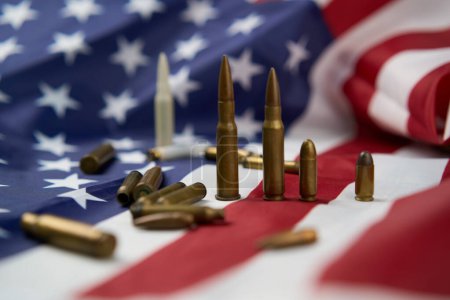 Großaufnahme von Patronen und Kugeln unterschiedlicher Größe, die auf der amerikanischen Flagge mit Sternen und Streifen angeordnet sind
