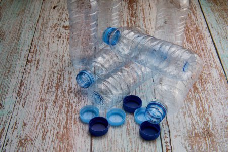 Blick von oben auf geschlossene und offene Plastikflaschen, die zum Recyceln auf einen Holztisch gestellt werden.