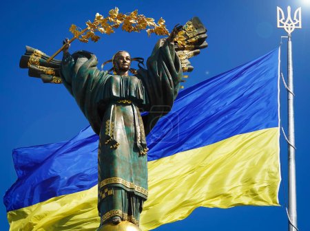 Foto de Kiev, Ucrania 20 de julio de 2020: Un monumento dedicado a la independencia de Ucrania en el contexto de la bandera más grande de Ucrania - Imagen libre de derechos