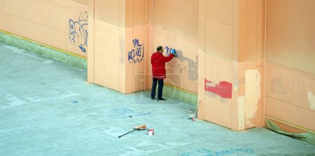 Photo for Kiev, Ukraine October 27, 2021: A man wipes off graffiti from a painted shop wall - Royalty Free Image