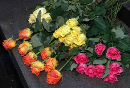 Bouquets of roses laid on black marble in memory of the deceased