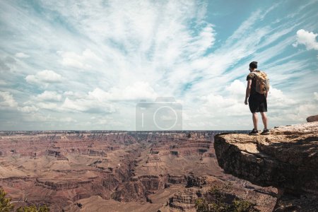Foto de Man with yellow backpack at the edge of the Colorado canyon. - Imagen libre de derechos