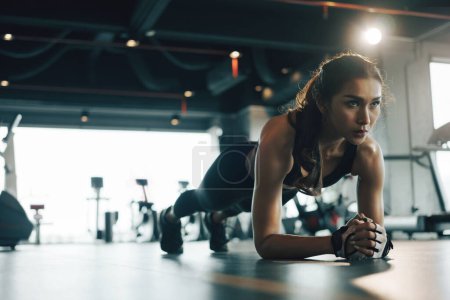 Foto de Mujer joven haciendo ejercicio de tablón mientras hace ejercicio en el gimnasio. - Imagen libre de derechos