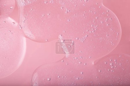 Vue du dessus du gel cosmétique liquide avec une structure pétillante sur fond rose..