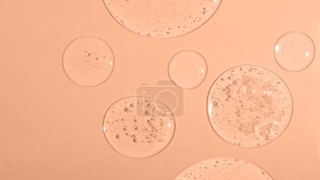 Top view of liquid cosmetics gel with bubbly structure on pastel background.Peach fuzz colored.