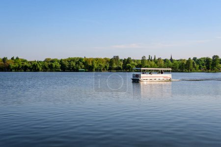 Téléchargez les photos : Bucharest, Romania - 5 May 2021:: Landscape with Herastrau lake and large green trees in King Michael I Park (Herastrau) in Bucharest, Romania,  in a sunny spring day - en image libre de droit