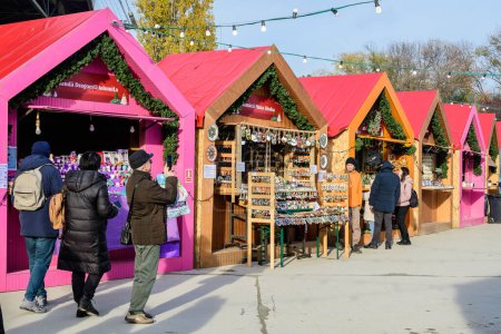Photo for Bucharest, Romania, 30 November 2023: Vivid colorful houses with traditional products for sale at the West Side Christmas Market in Drumul Taberei neignbourhood, in a sunny cold day with blue sky - Royalty Free Image