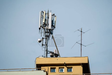 Photo for Telecommunications antennas on a rooftop of an old building with clear blue sky in the background - Royalty Free Image