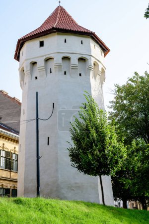 Large old white painted stone tower in the historical center of the Sibiu city, near Citadel Street and Park (Strada si Parcul Cetatii), in Transylvania (Transilvania) region of Romania, in summer
