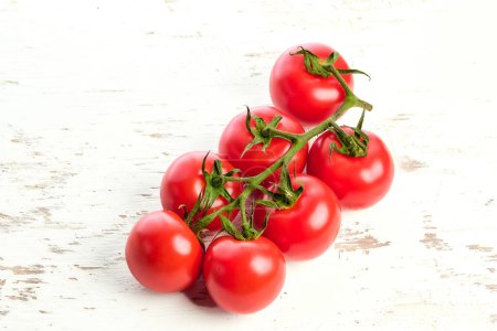Sprigs of ripe cherry tomatoes on a white wooden surface. Close-up of cherry tomatoes