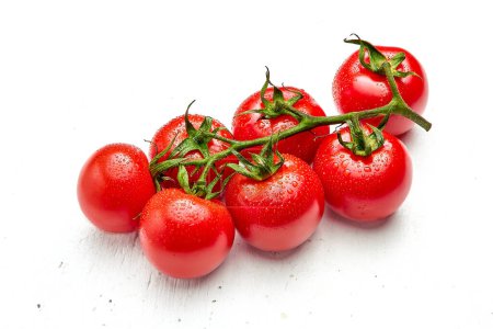 Tomates cerises avec gouttelettes d'eau sur fond blanc texturé en bois. Gros plan sur les tomates cerises
