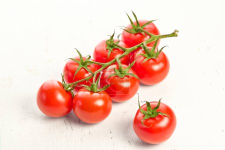 Tomates cerises sur fond blanc texturé en bois. Gros plan sur les tomates cerises