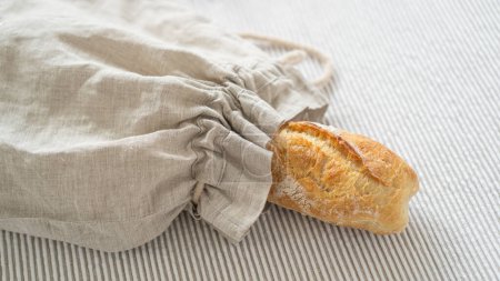 Artisanal ciabatta showcased in a sustainable linen bag, atop a wooden table adorned with a lovely tablecloth. Delicious Italian ciabatta displayed on a clean white backdrop.