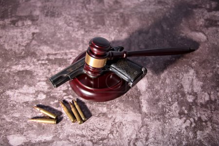 Photo for Gun under a judges gavel. Concept of use of arms and justice - Royalty Free Image