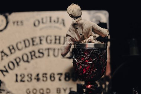 Eine düstere Atmosphäre mit Ouija-Tafel, Kerzen und mystischen Objekten, die ein Gefühl des Okkulten heraufbeschwören