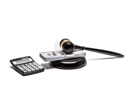 A legal gavel atop American currency with a calculator, depicting financial law or fines