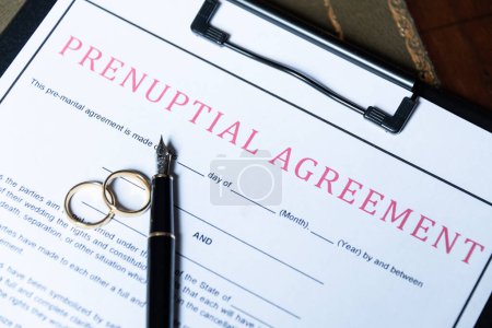 Nahaufnahme eines Ehevertragsformulars mit Eheringen und Füllfederhalter, das die rechtlichen Aspekte der Ehevorbereitung aufzeigt