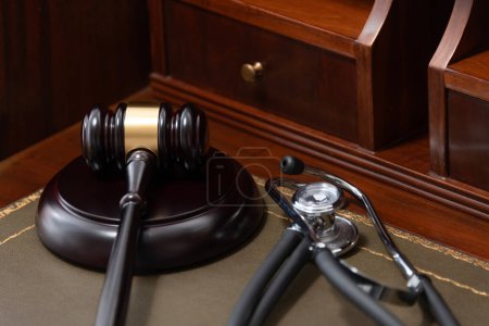 Eine Nahaufnahme eines Richtergabel und eines schwarzen Stethoskops auf einem juristischen Buch, das die Kreuzung von Recht und Medizin symbolisiert