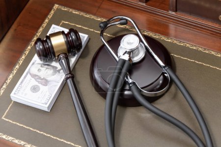 Ein Bild, das einen Richtergabel, ein medizinisches Stethoskop und einen Stapel US-Währung zeigt, unterstreicht die kostspielige Natur rechtlicher und medizinischer Dienstleistungen