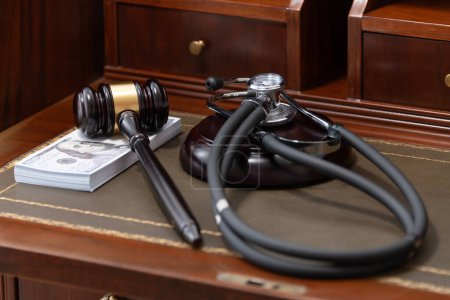 Ein Bild, das einen Richtergabel, ein medizinisches Stethoskop und einen Stapel US-Währung zeigt, unterstreicht die kostspielige Natur rechtlicher und medizinischer Dienstleistungen