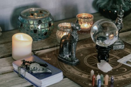Eine stimmungsvolle Kulisse mit Kristallkugel, ägyptischen Katzenstatuen, Kerzen und Kristallen, die ein mystisches Ambiente schaffen