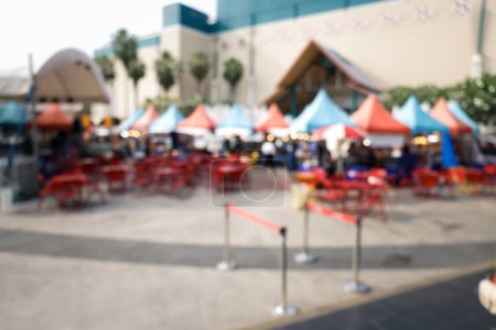 Photo for Blurred image of food fair, flea market or food festival consist of booth, tent, vendor and food stall. Busy with asian people along walking street. Event in Chiang Mai at twilight for background. - Royalty Free Image