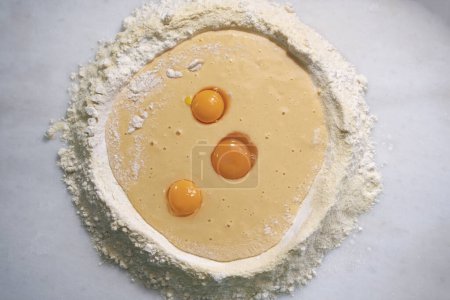 Broken eggs on flour, means for making pasta.