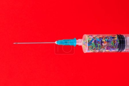 Foto de A classic disposable syringe filled with symbolic hearts. Love concept. Background with copy space for text. Red backdrop. - Imagen libre de derechos