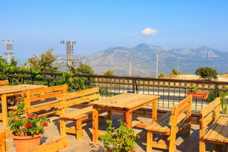 Photo for Wooden tables on the terrace of a restaurant in the mountains with a beautiful view. Popular places among tourists. Southern coastal Taurus Mountains in Turkey - Royalty Free Image