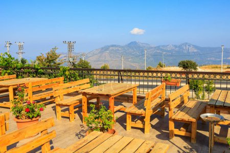 Photo for Wooden tables on the terrace of a restaurant in the mountains with a beautiful view. Popular places among tourists. Southern coastal Taurus Mountains in Turkey - Royalty Free Image