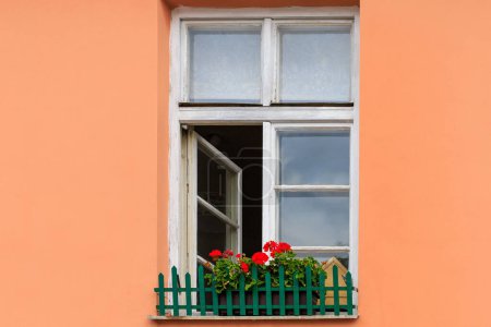 Foto de Very beautiful classic wooden window with flowers on the windowsill in minimalist European architecture. Cozy tourist town. Background or backdrop - Imagen libre de derechos