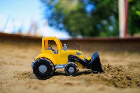 Téléchargez les photos : Pelle à jouets dans le bac à sable pour enfants. Contexte avec mise au point sélective et espace de copie - en image libre de droit